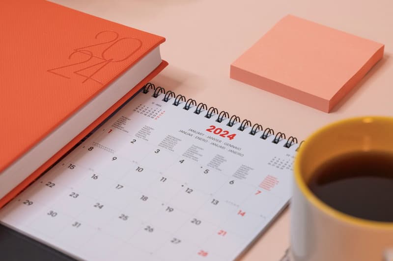 Open calendar with a terracotta planner and coffee mug on a warm desk