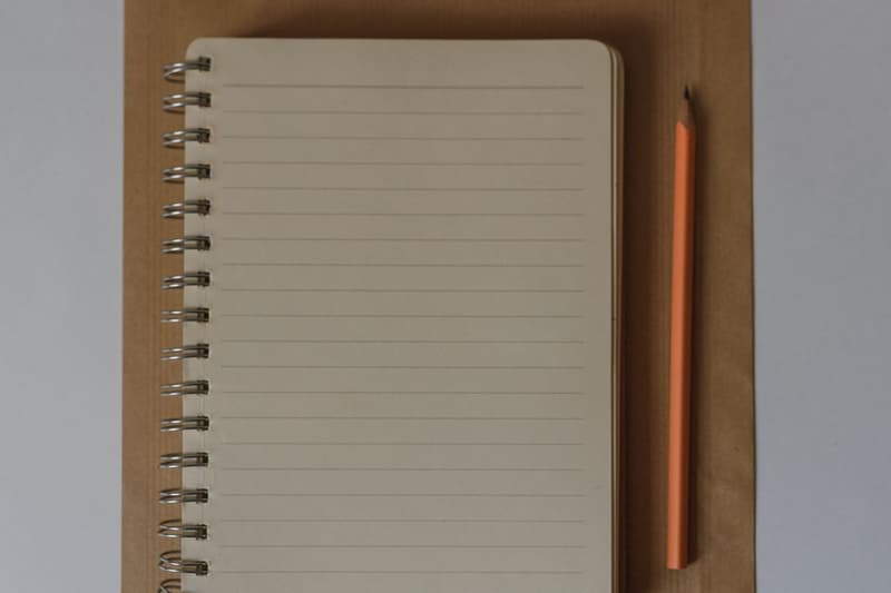 Spiral notebook and pencil on a kraft paper envelope